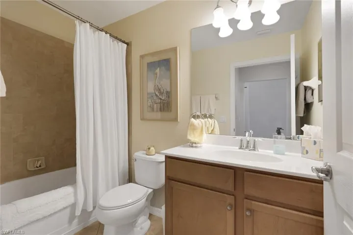 Full guest bath with shower / bath combo with shower curtain, vanity, and a chandelier