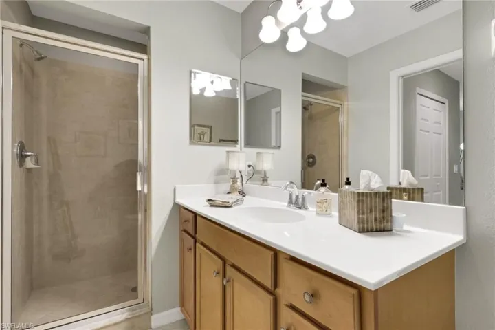 Full bath featuring vanity, a shower stall, and a chandelier