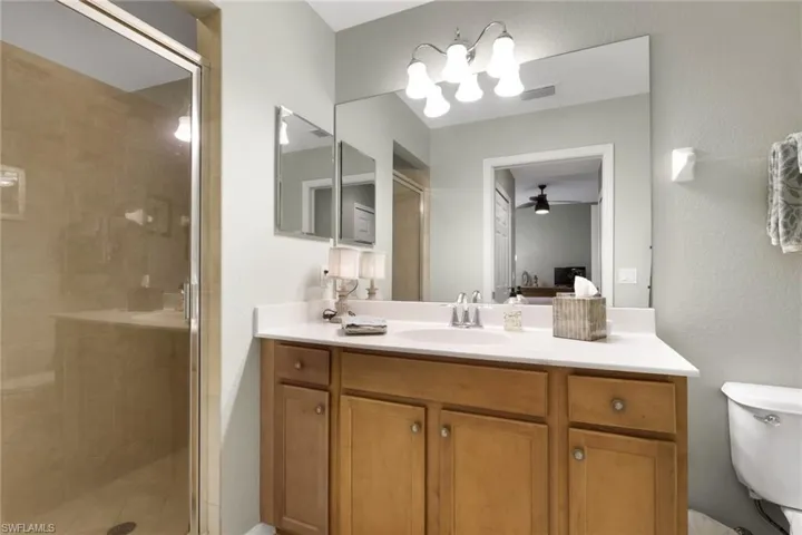 Ensuite bathroom featuring a stall shower, vanity, a ceiling fan, and a chandelier