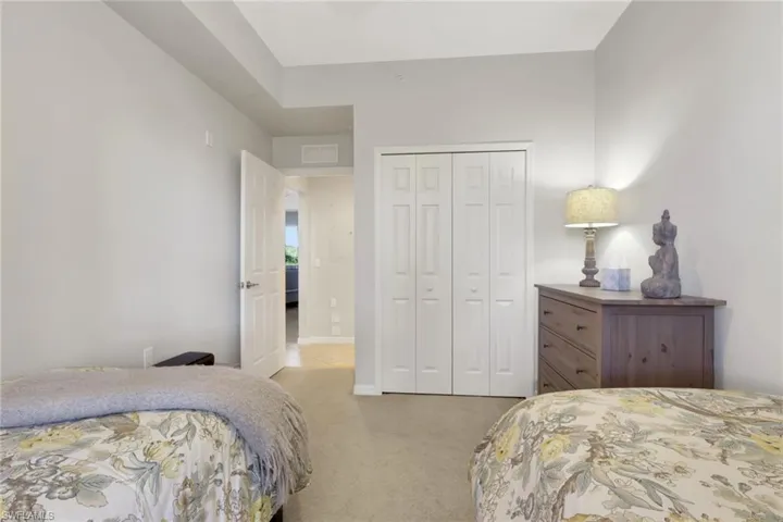 Guest bedroom with light colored carpet and a closet
