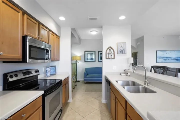 Kitchen with stainless steel appliances, wood finish cabinetry, light tile patterned floors, and recessed lighting