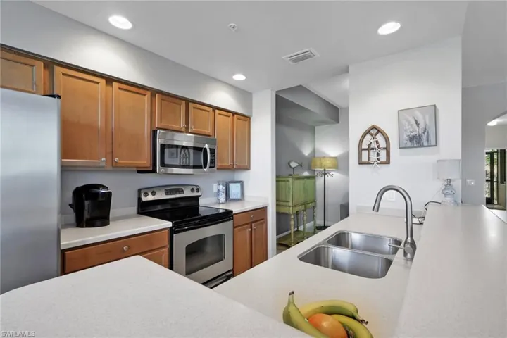 Kitchen with stainless steel appliances, wood finish cabinets, recessed lighting, and light stone countertops
