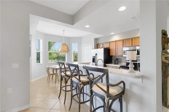 Kitchen featuring a kitchen bar, light countertops, stainless steel appliances, custom light fixtures, and dining area
