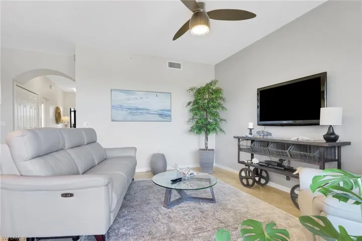 Tiled living room featuring a ceiling fan and arched walkways