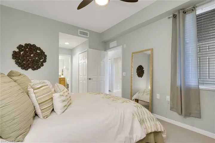 Carpeted bedroom featuring ensuite bathroom, a closet, and ceiling fan