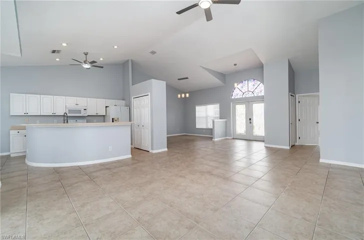 Unfurnished living room featuring ceiling fans, high vaulted ceiling, light tile patterned flooring