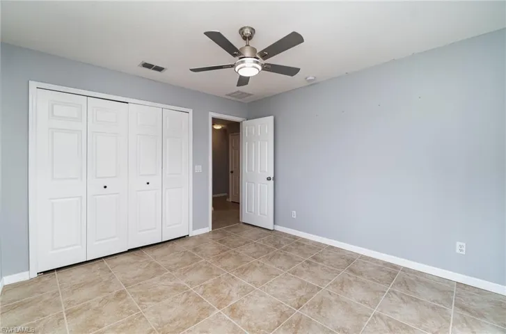 Unfurnished bedroom with a closet, light tile patterned flooring, baseboards, and a ceiling fan