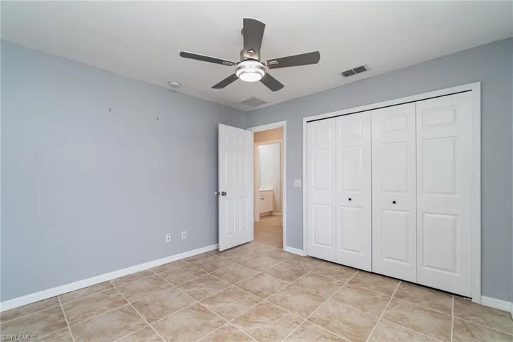 Unfurnished bedroom featuring baseboards, light tile patterned floors, a closet, and ceiling fan