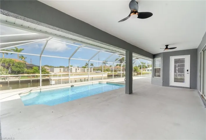 Swimming pool featuring a ceiling fan, a patio area, a water view, and a huge under tress lanai.  Door leads to breakfast nook.  Sliders to main living area.