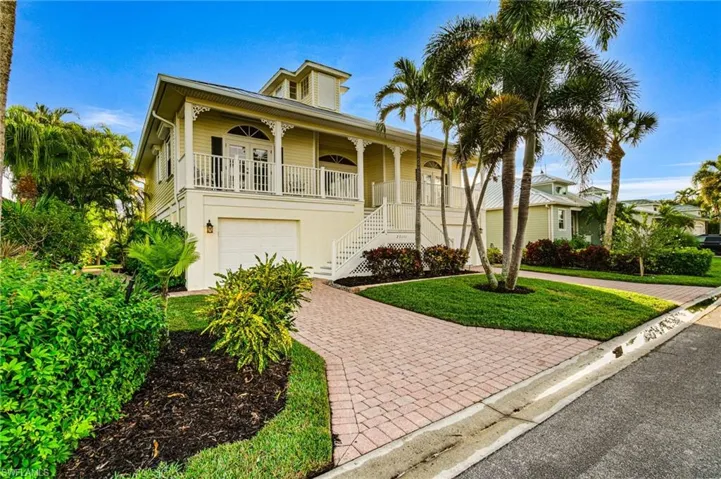 View of front of home featuring covered porch, decorative driveway, a front lawn, stairway, and a garage