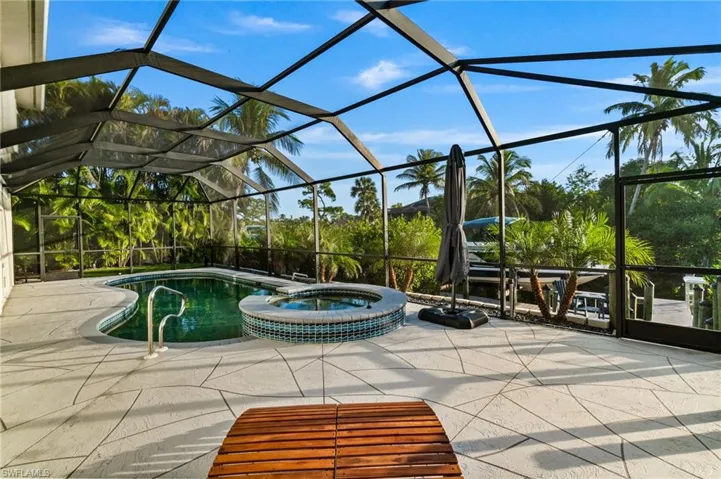 View of pool with a sunroom, a pool with connected hot tub, and glass enclosure