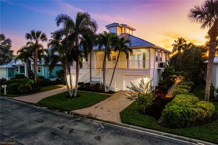 View of front of home with stairs, decorative driveway, an attached garage, and a yard