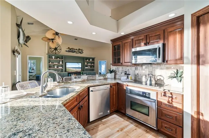 Kitchen with light stone countertops, a breakfast bar, appliances with stainless steel finishes, recessed lighting, and light wood-type flooring