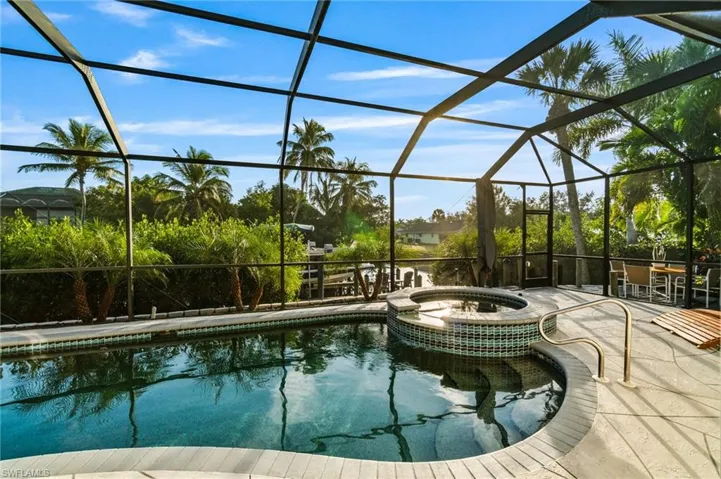 View of pool featuring a sunroom, a pool with connected hot tub, and glass enclosure