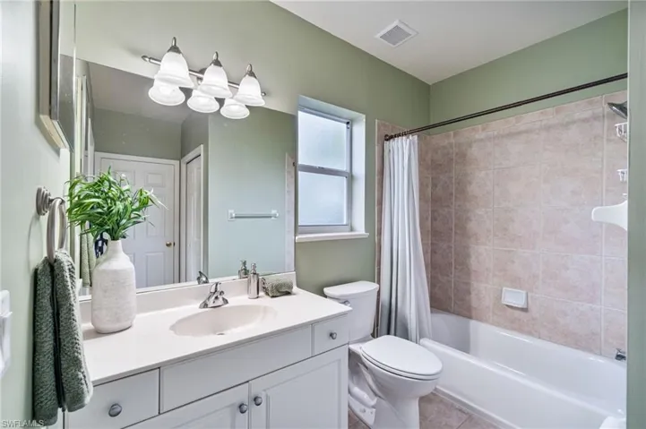 Bathroom with vanity, shower / bath combo, and light tile patterned flooring
