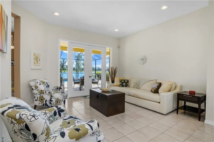 Living room featuring french doors, a water view, and light tile patterned floors