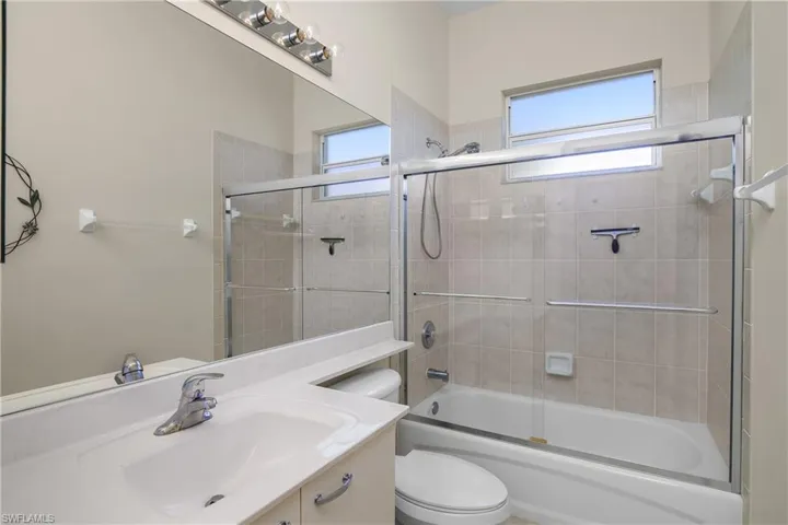 Full bathroom with combined bath / shower with glass door, vanity, and toilet