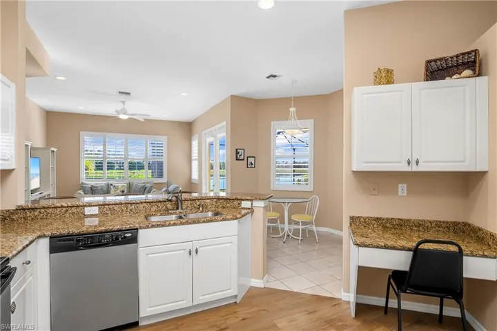Kitchen with kitchen peninsula, appliances with stainless steel finishes, light wood-type flooring, dark stone counters, and white cabinetry