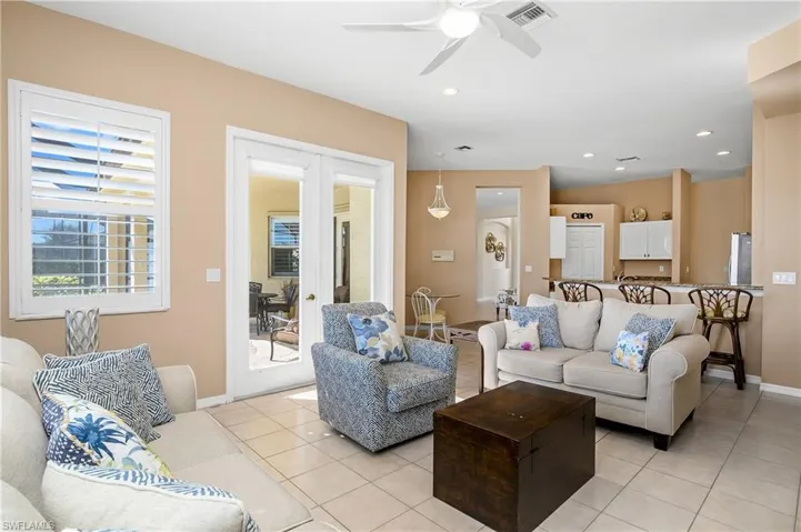 Tiled living room featuring ceiling fan and french doors