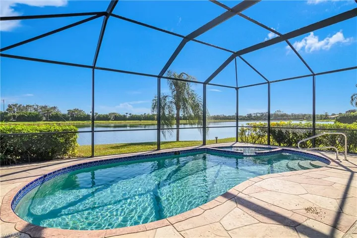 View of swimming pool featuring a lanai, an in ground hot tub, a water view, and a patio