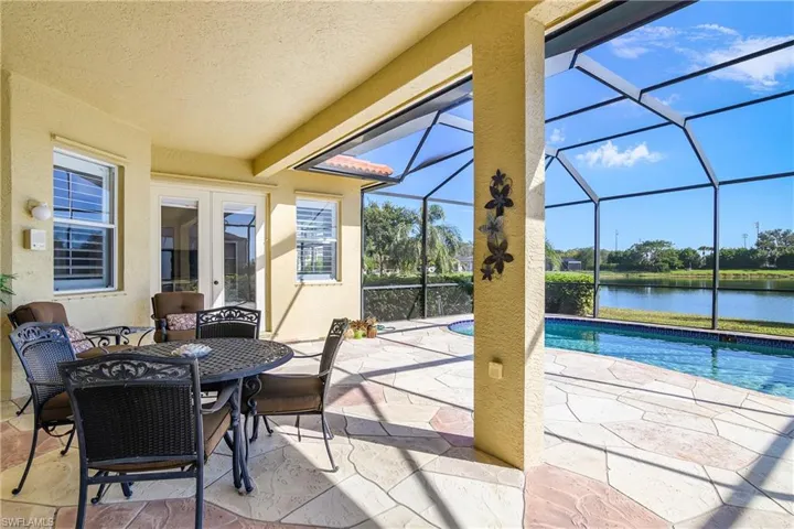 View of patio with glass enclosure, a water view, and french doors