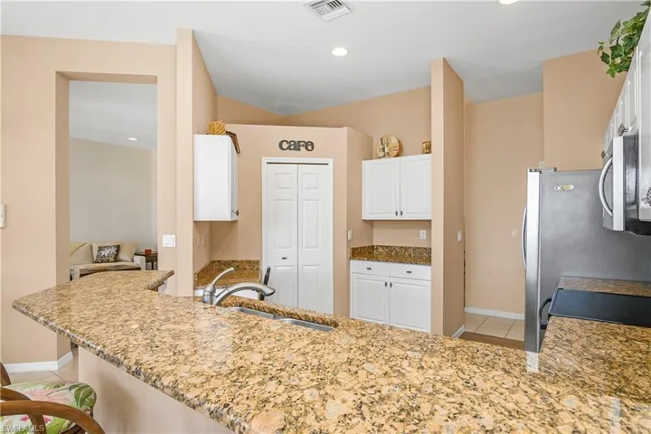 Kitchen with white cabinets, kitchen peninsula, sink, and appliances with stainless steel finishes