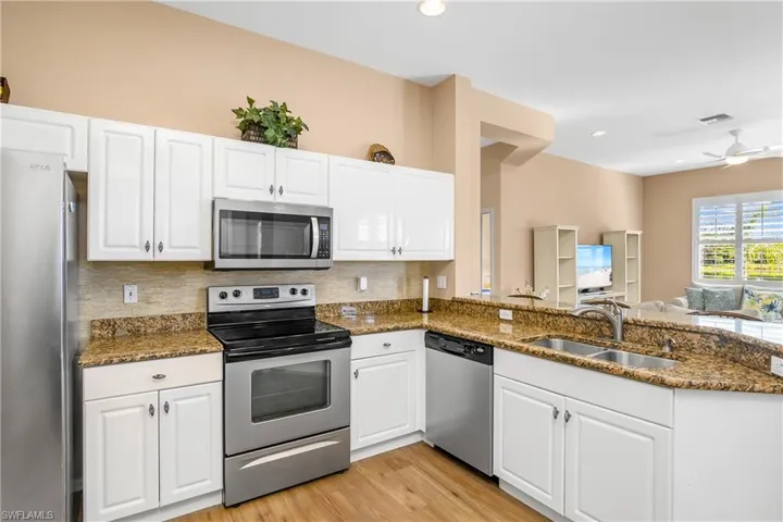 Kitchen with kitchen peninsula, white cabinetry, sink, and stainless steel appliances