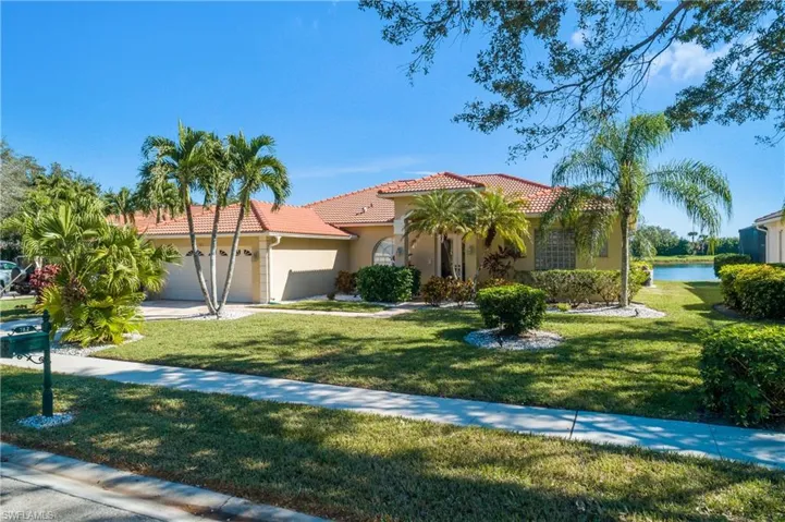 Mediterranean / spanish home featuring a water view, a garage, and a front lawn