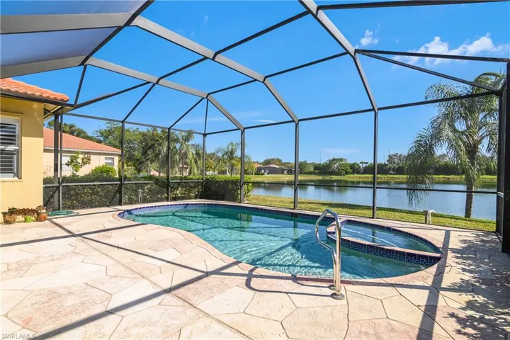 View of pool with a lanai, a patio area, a water view, and an in ground hot tub