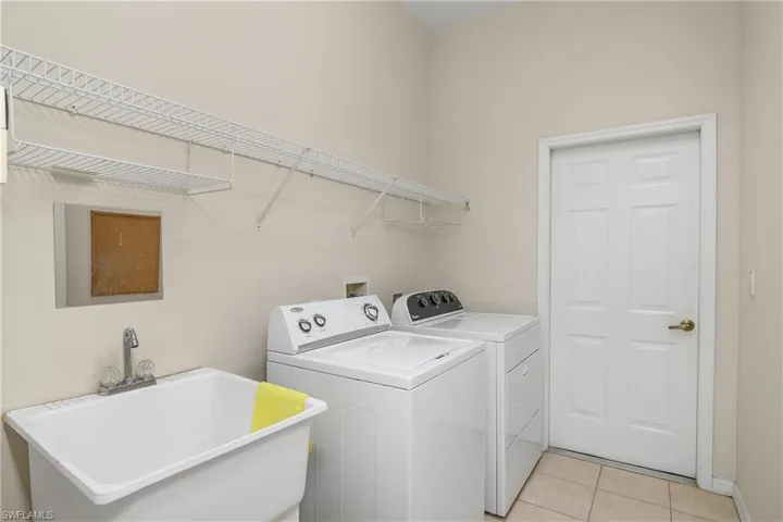 Laundry area featuring independent washer and dryer, sink, and light tile patterned floors