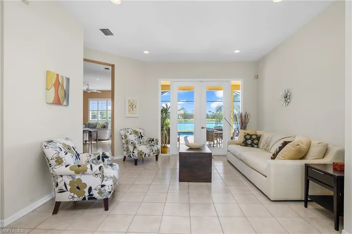 Living room with ceiling fan, french doors, and light tile patterned floors