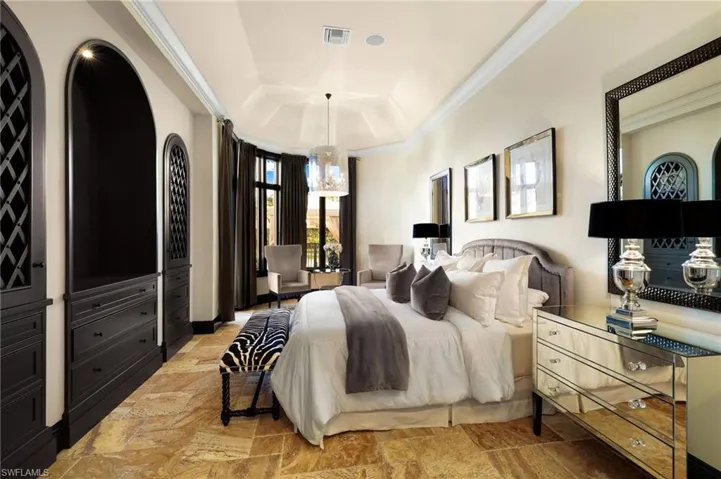 Bedroom featuring a raised ceiling, crown molding, and a chandelier