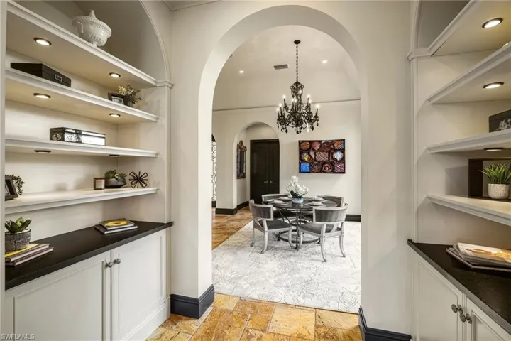 Dining room featuring recessed lighting, built in shelves, a chandelier, stone tile flooring, and arched walkways