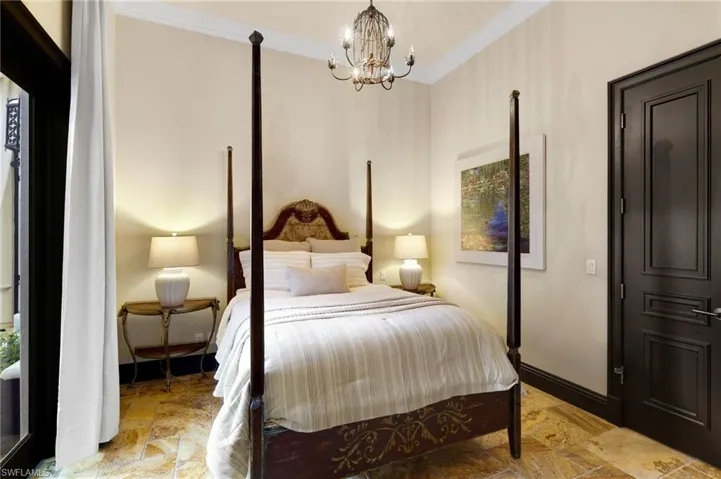 Bedroom with ornamental molding, a chandelier, and light stone finish flooring
