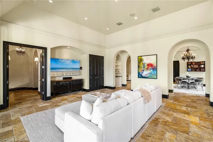 Living area featuring a chandelier, stone tile flooring, arched walkways, and recessed lighting