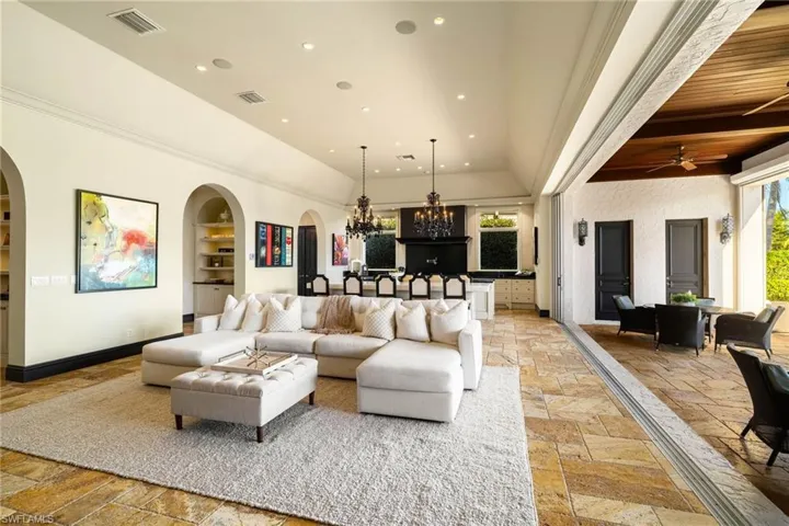 Living area with a chandelier, stone tile flooring, recessed lighting, arched walkways, and ceiling fan