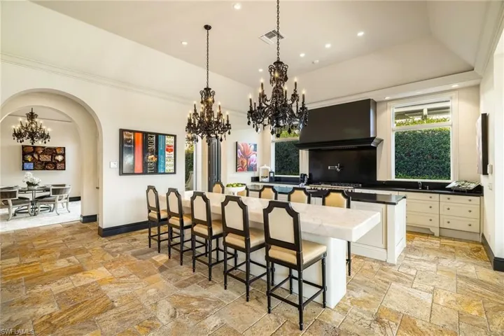 Kitchen featuring a chandelier, a kitchen bar, hanging light fixtures, recessed lighting, and arched walkways