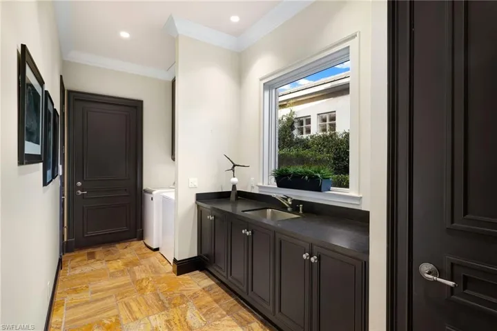 Laundry area with crown molding, washing machine and dryer, light stone finish flooring, recessed lighting, and cabinet space