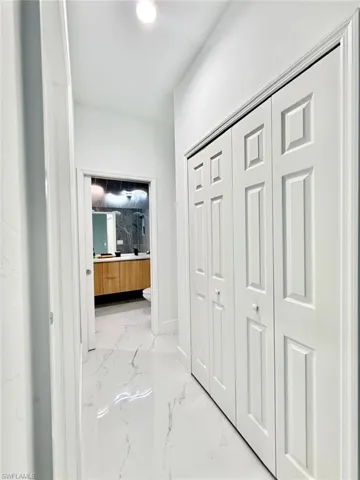 Hallway with light marble finish flooring and baseboards