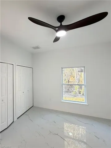 Unfurnished bedroom featuring multiple closets and a ceiling fan