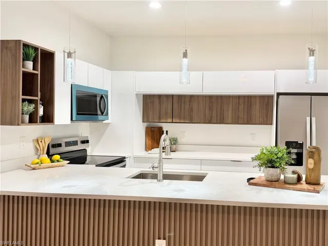 Kitchen with pendant lighting, light stone countertops, stainless steel appliances, open shelves, and modern cabinets