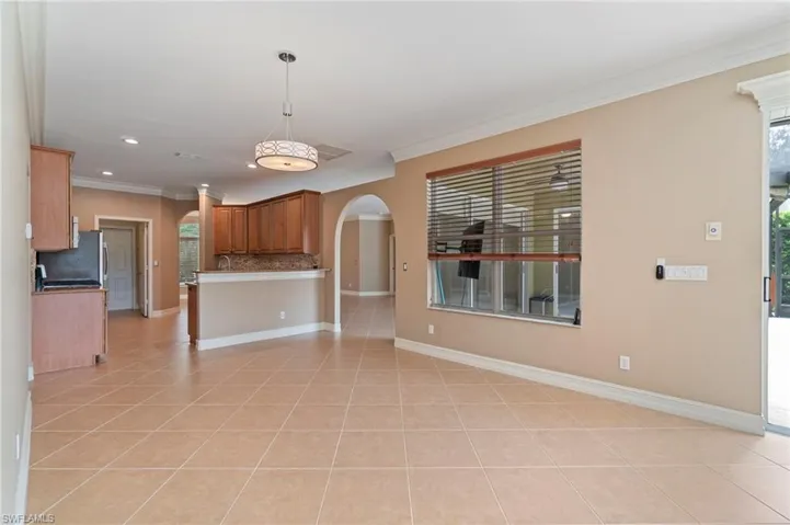 Kitchen with arched walkways, open floor plan, light tile patterned floors, crown molding, and tasteful backsplash