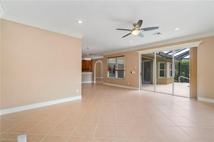 Empty room with ceiling fan, ornamental molding, arched walkways, light tile patterned floors, and recessed lighting