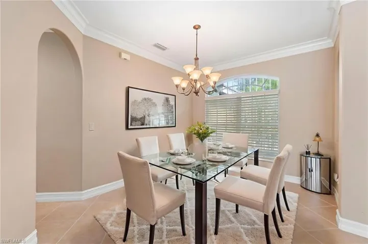Dining area featuring a chandelier, crown molding, light tile patterned flooring, and arched walkways