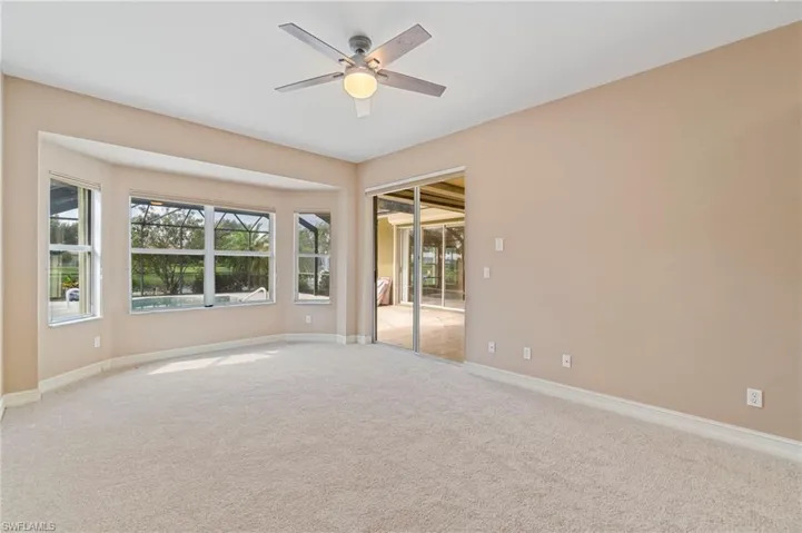 Empty room with light colored carpet, plenty of natural light, and ceiling fan