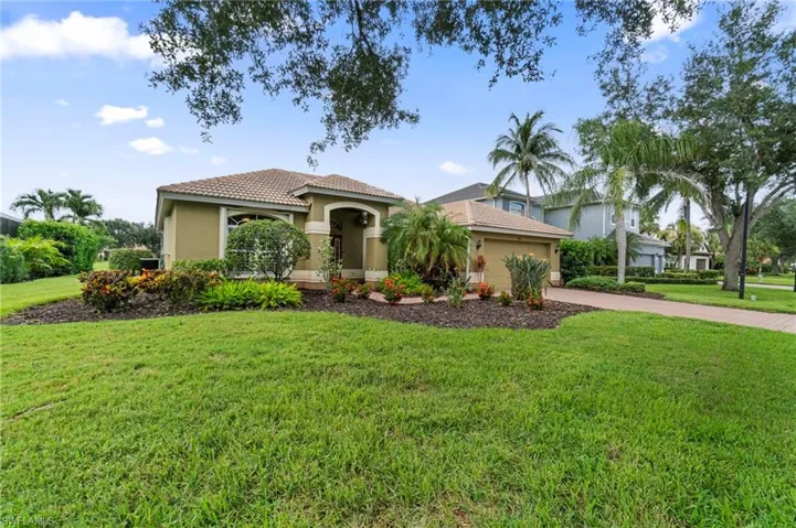 Mediterranean / spanish home with a tile roof, stucco siding, an attached garage, and a front yard
