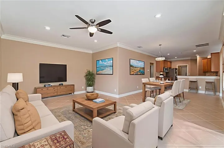 Living area with light tile patterned floors, crown molding, ceiling fan, and recessed lighting