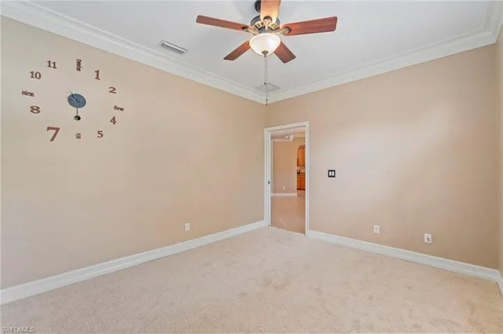 Unfurnished room featuring light carpet, ceiling fan, crown molding, and arched walkways
