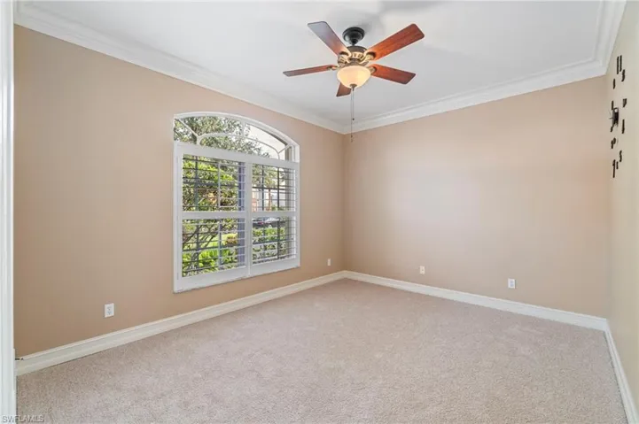 Carpeted spare room with crown molding and a ceiling fan