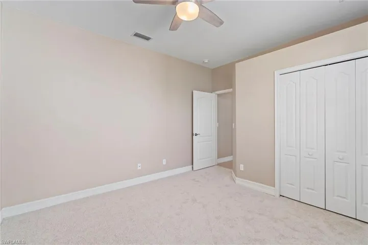 Unfurnished bedroom with light colored carpet, a closet, and a ceiling fan